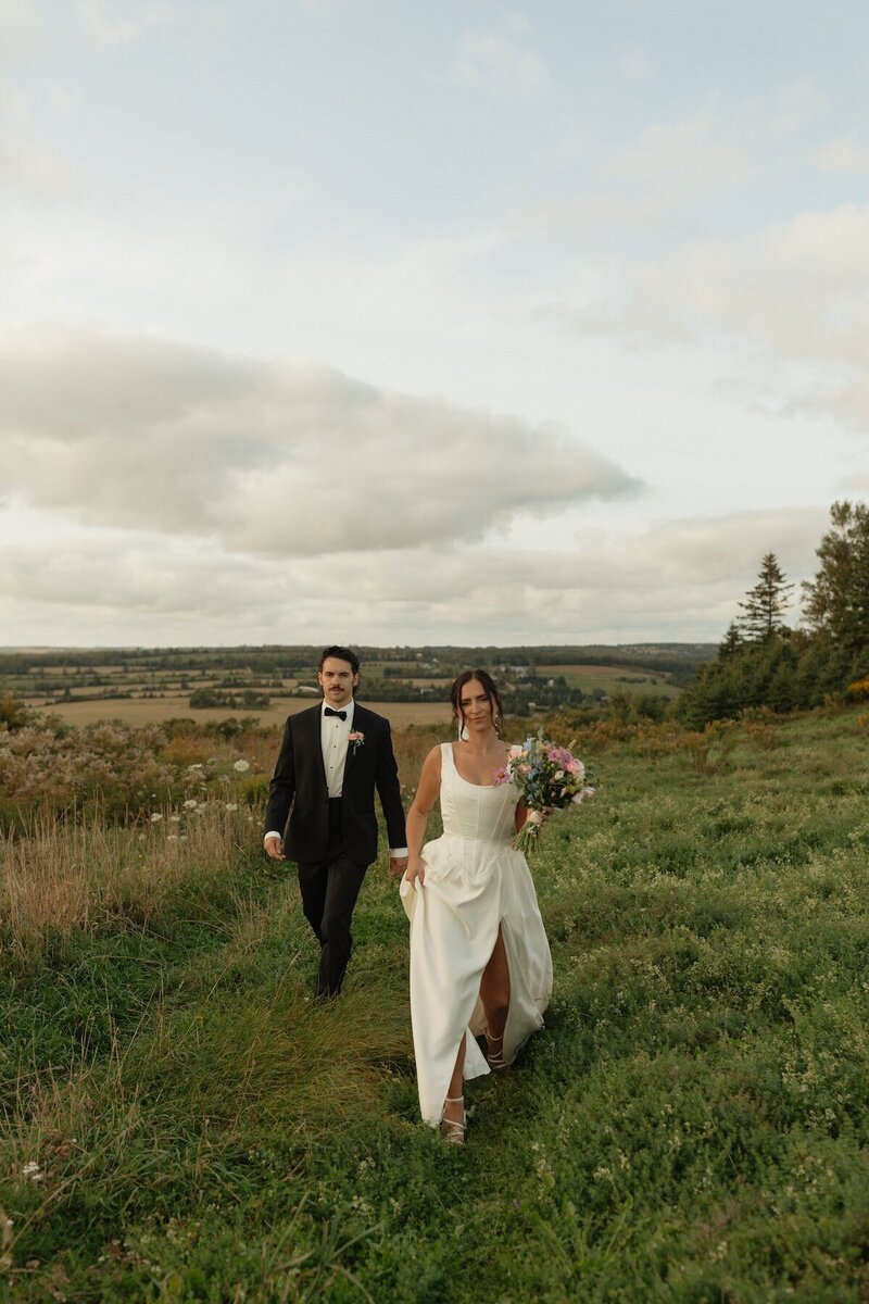 bride and groom in field on wedding day at prince edward island