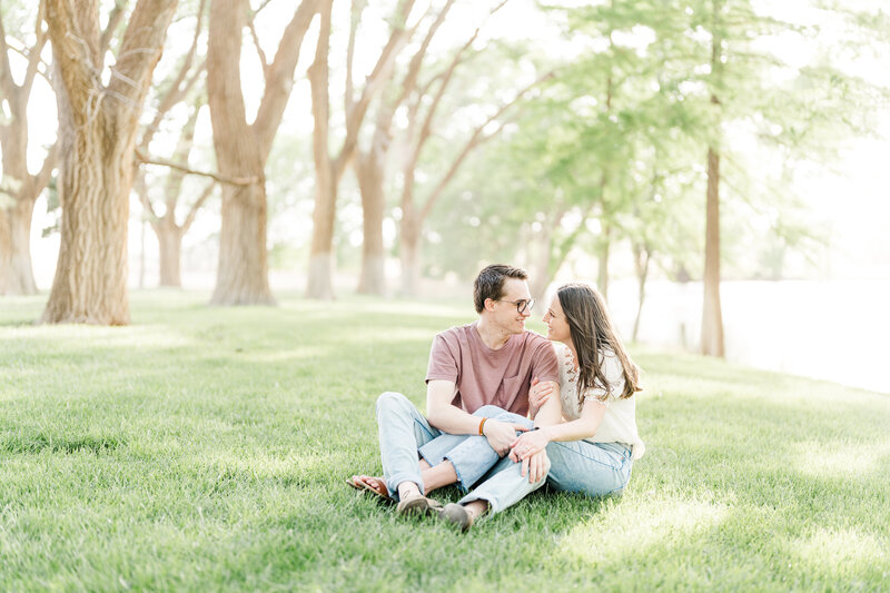 engagement photos with a couple sitting down in grass, wearing a casual  outfit for engagement photos