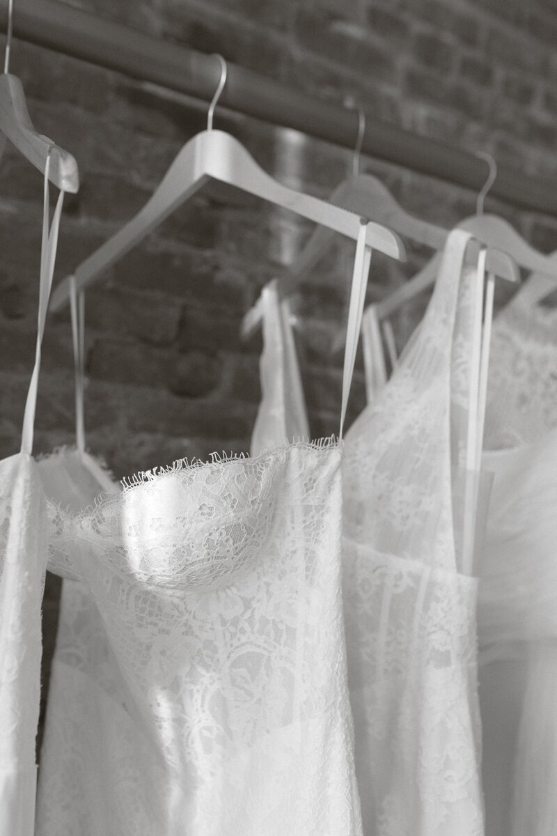 Close-up of lace wedding dresses hanging on wooden hangers.