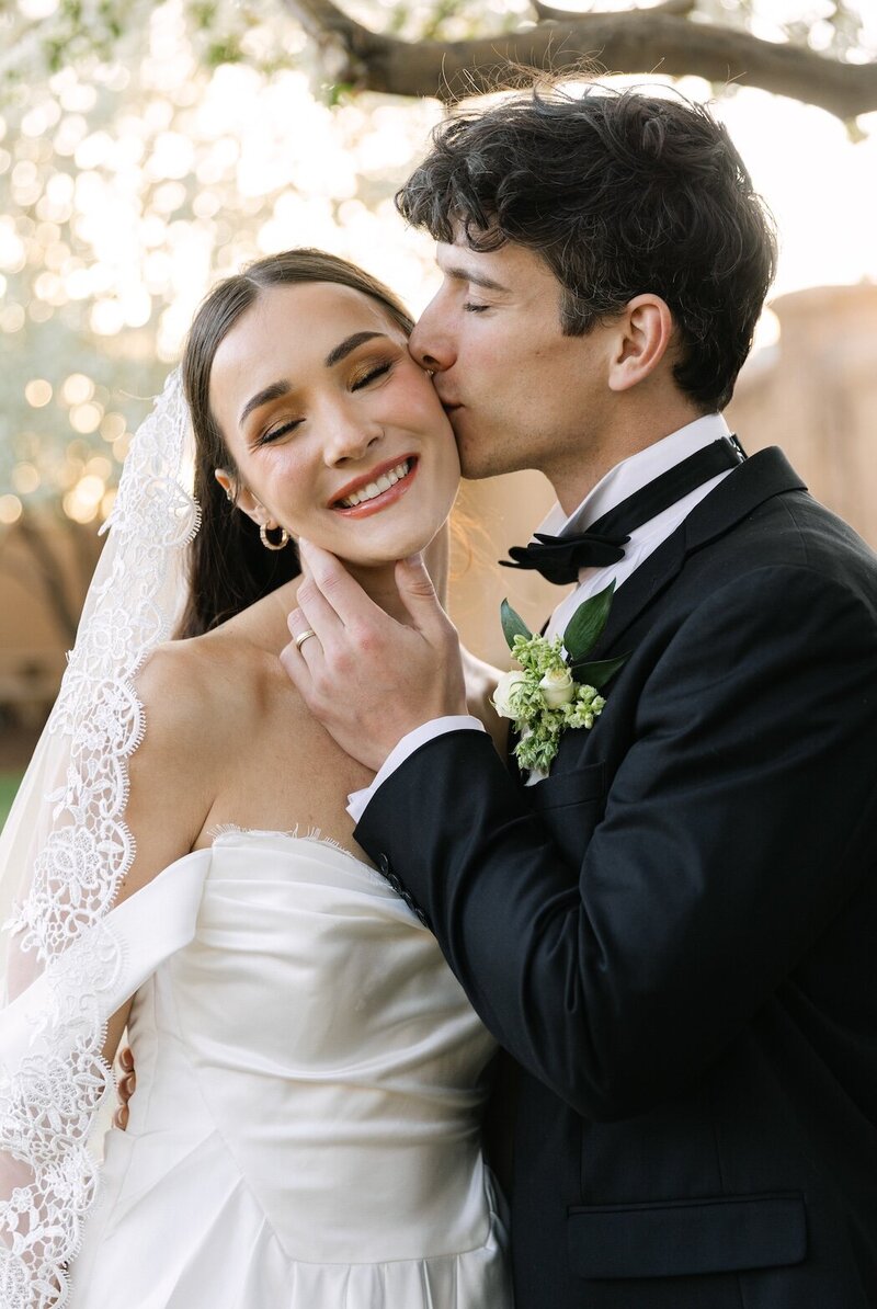 Groom kissing his bride’s cheek during golden-hour portraits at their Colorado wedding at Villa Parker.