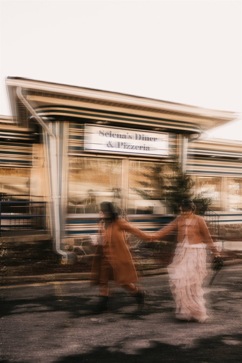 Blurry image of lesbians running through diner parking lot who just eloped