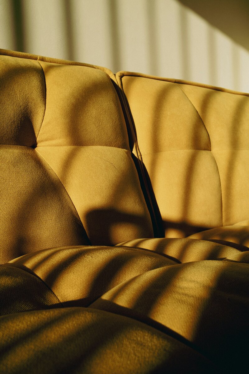 Close up of yellow couch with shadows streaking across