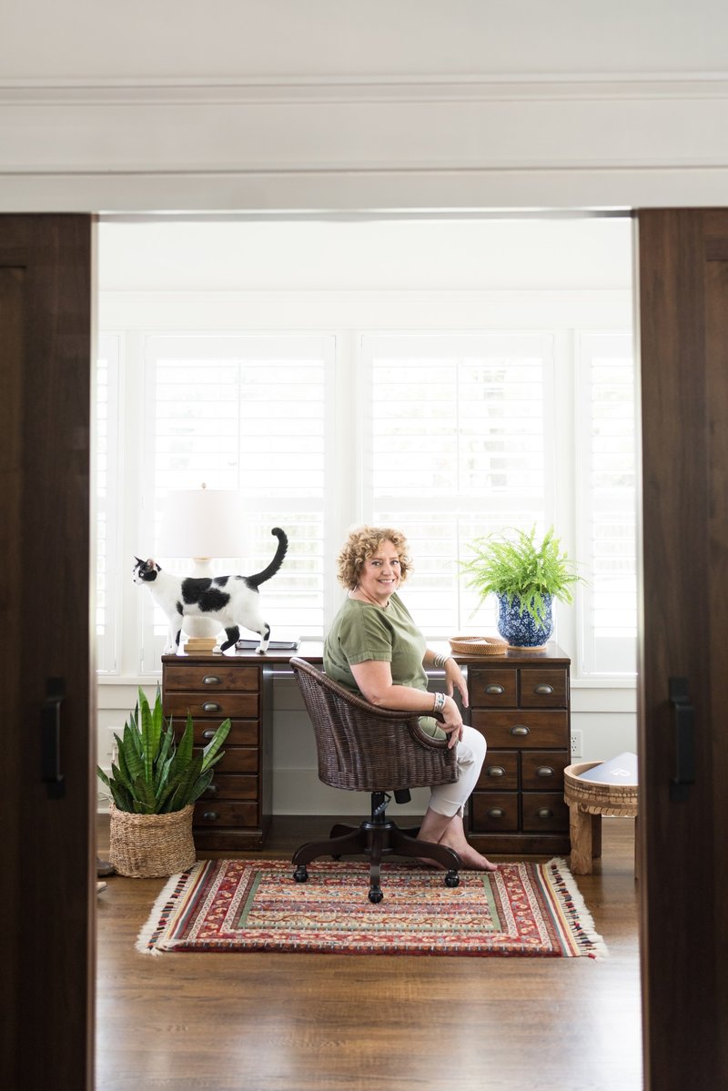 Nashville realtor sitting at her wooden desk with a black and white cat walking across the desk