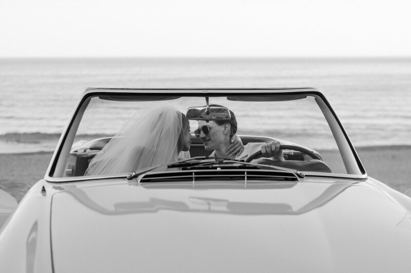 bride and groom kissing in a classic car