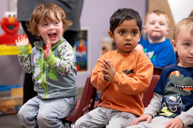 children smiling and clapping at daycare