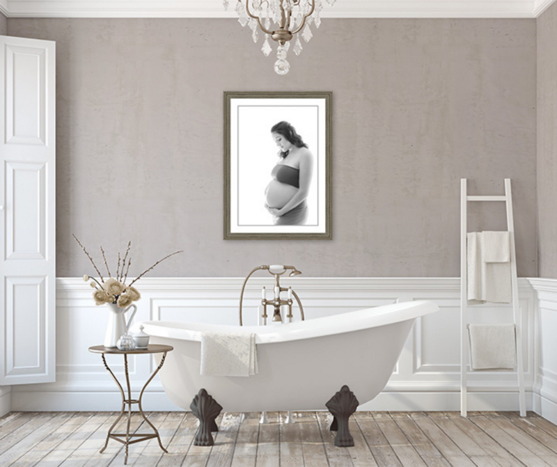 Charlotte maternity photographer captures the timeless beauty of a Native American mom-to-be in a black and white portrait. Luxurious bathroom setting with clawfoot tub, florals, and crystal chandelier creates a soft, elegant atmosphere.