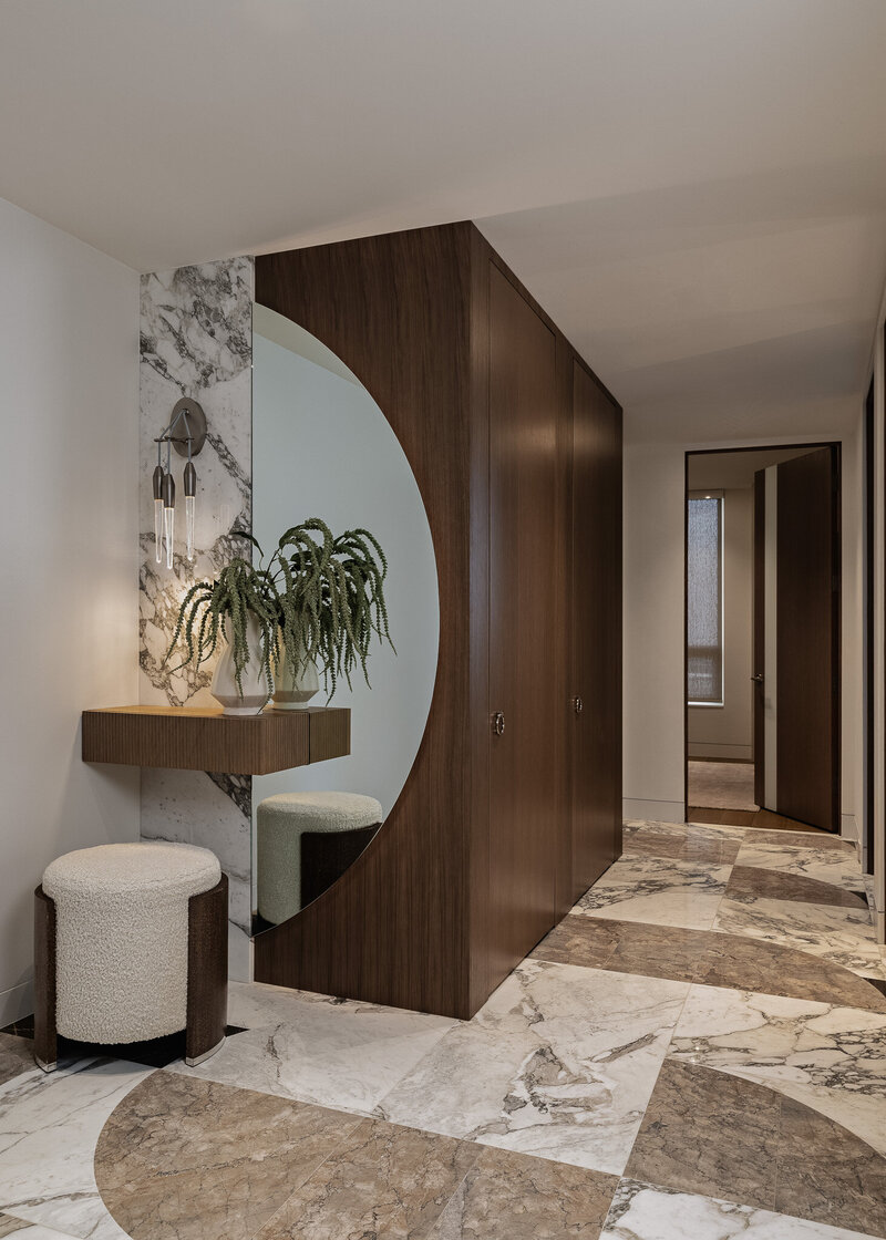 An elegant, all custom entry with semi circle mirror, hidden doors and hand-cut stone floor in Salt Lake City, designed by Sister Studio.