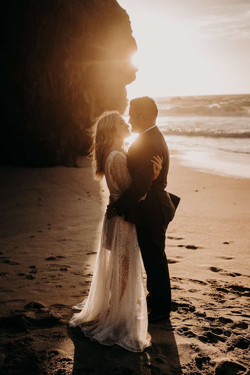 focus on the brides wedding ring on her ring as the bride and groom kiss in the background