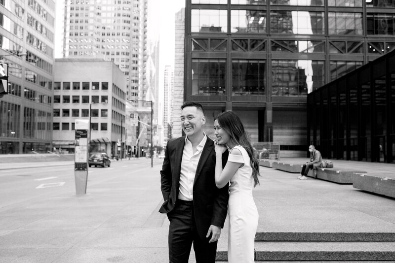 Modern Editorial Couple smile candid moment embracing sweetly during engagement session at Toronto Financial District Hailey Bieber inspired bride | Jacqueline James Photography