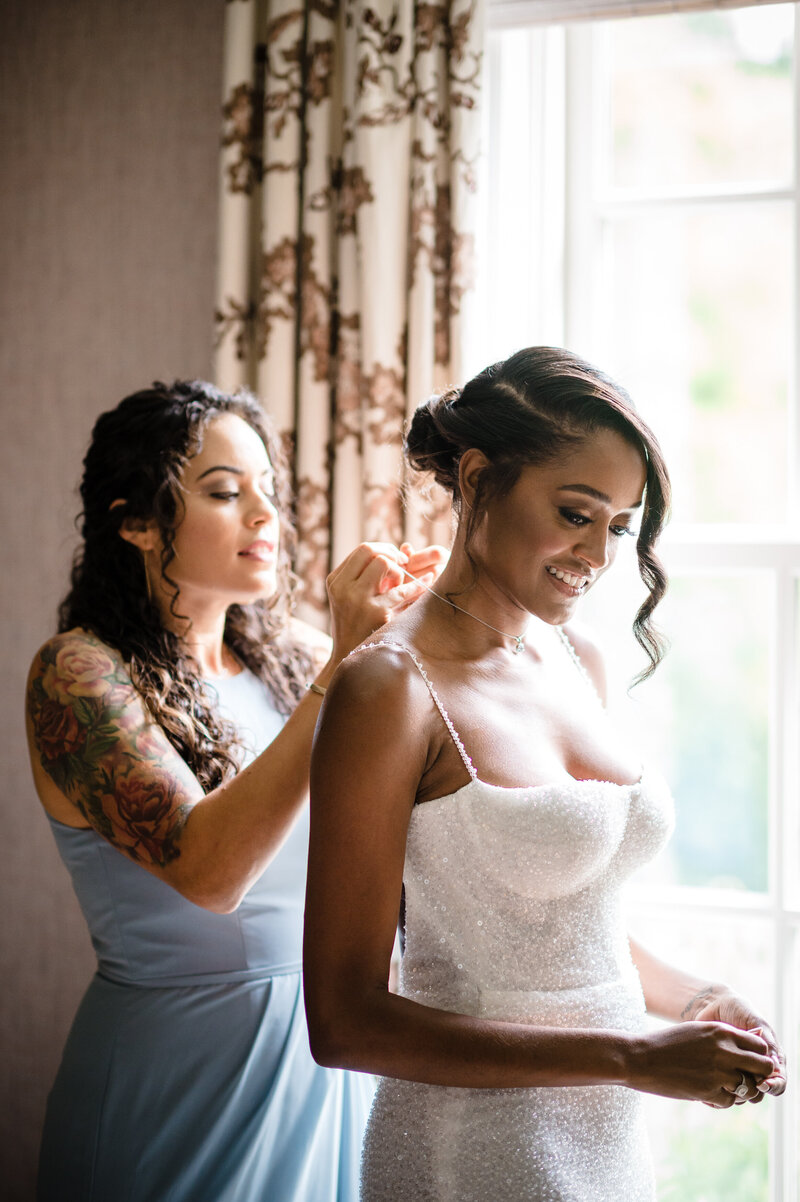 Bride getting helped into wedding dress at Mayflower Inn and Spa, by Teresa Johnson Photography