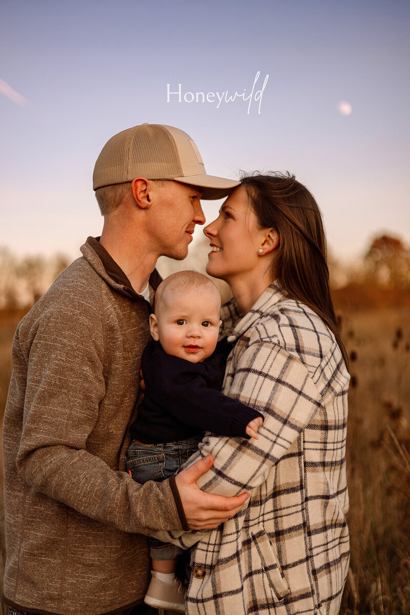 A family of four sitting on the sand at a West Michigan beach during sunset, sharing a warm and intimate moment during a lifestyle family photography session.