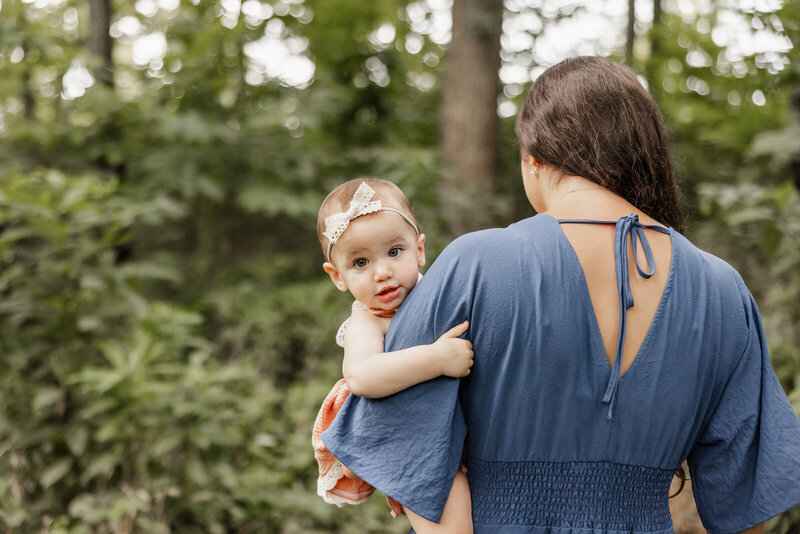 Baby looking of mother's shoulders while mother walks away from camera. 