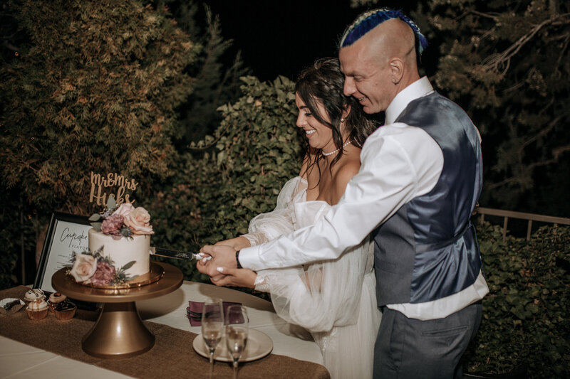 edgy boho bride and groom  cutting their wedding cake in sedona