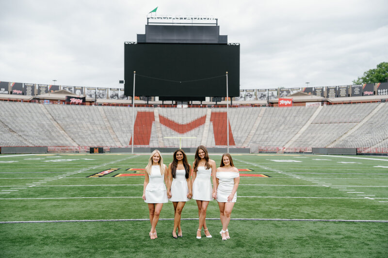 Nursing graduates celebrating their graduation with photos on the turf at The University of Maryland's SECU Stadium