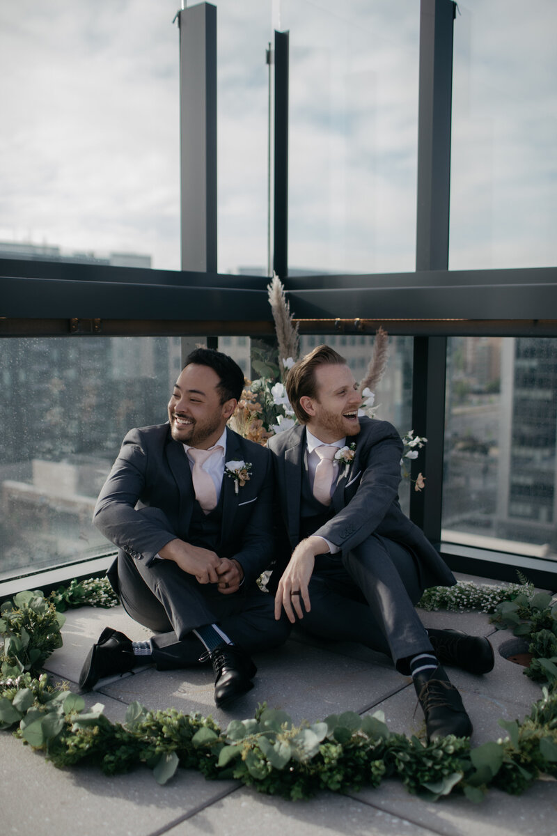Male couple sitting on Denver rooftop looking off into the city
