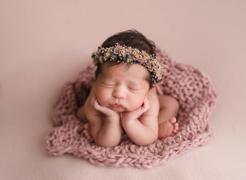 newborn girl posed as froggie, on a pink backdrop
