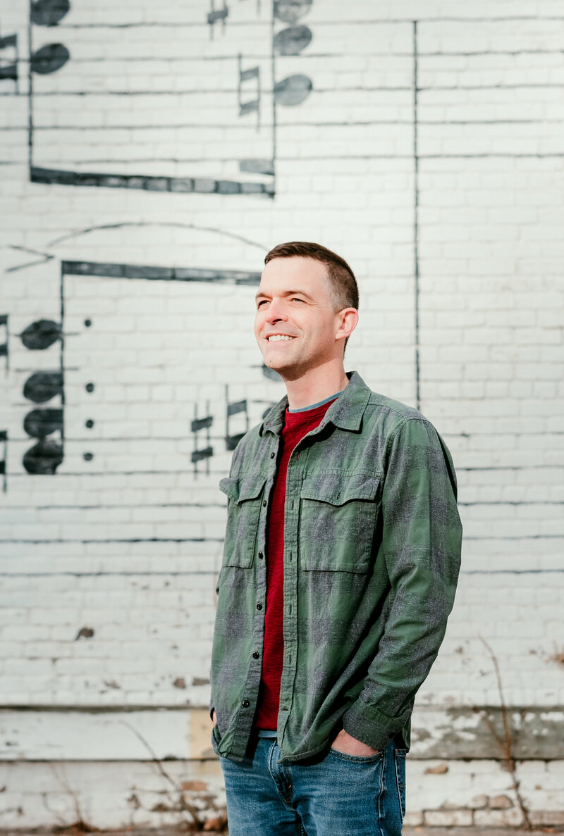 Casual dating profile photo of a Minneapolis man a white textured music wall, captured for modern online dating apps.