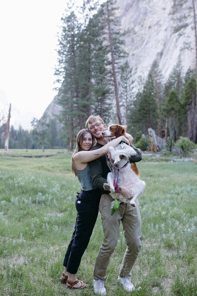 A couple poses for a photo with a Brittany dog in Yosemite National Park