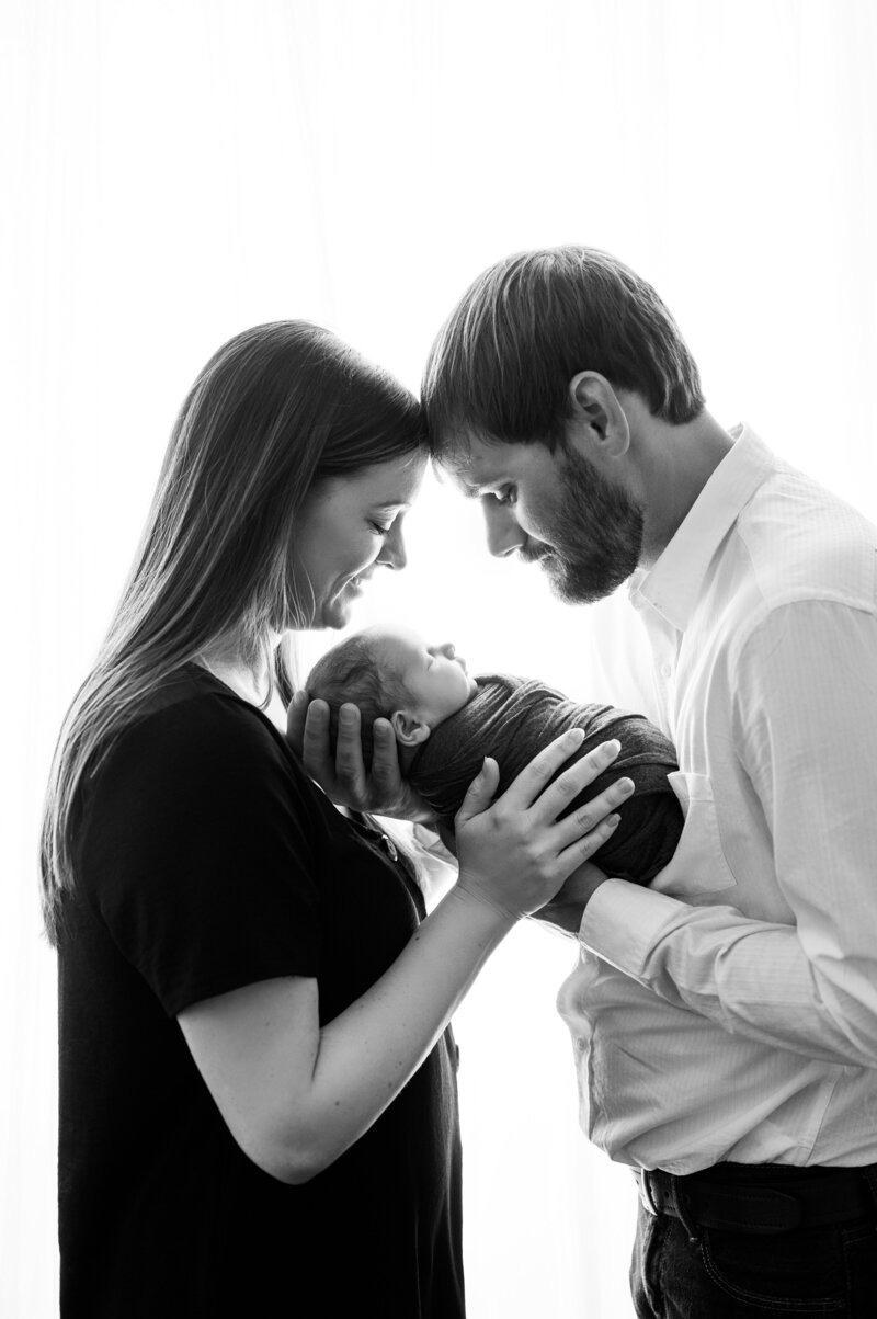 Happy parents smiling with their newborn baby during a photography session in Houma studio