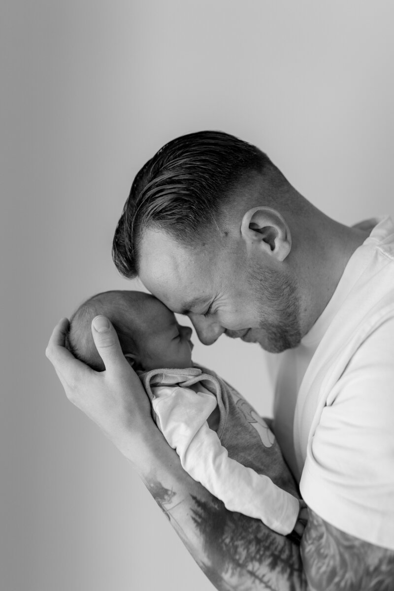 Schwarz weiss Bild von Vater der Baby gegen seine Stirn haelt