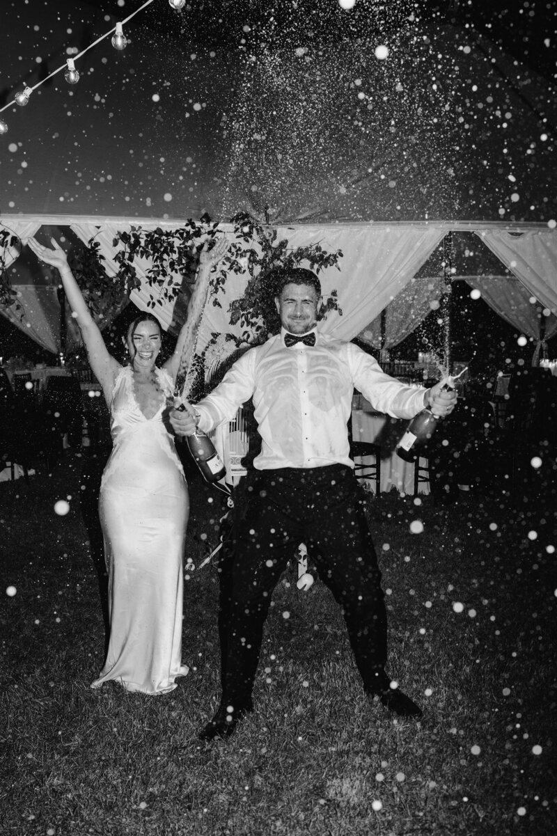 bride and groom black and white popping champagne bottles
