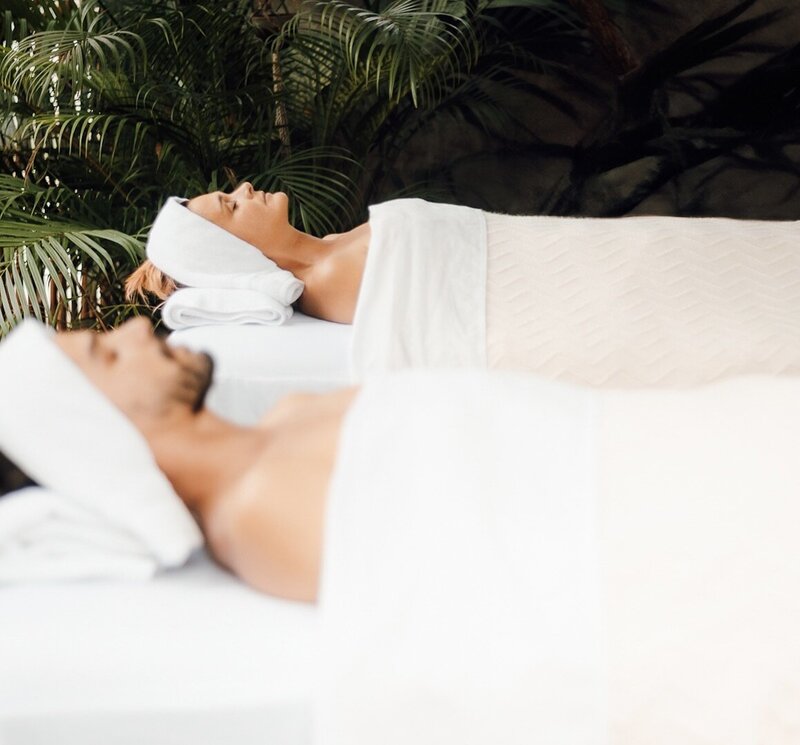 Couple in deep relaxation after a yoga and meditation session at Livin Wellness in Tulum, resting peacefully in a lush tropical setting.