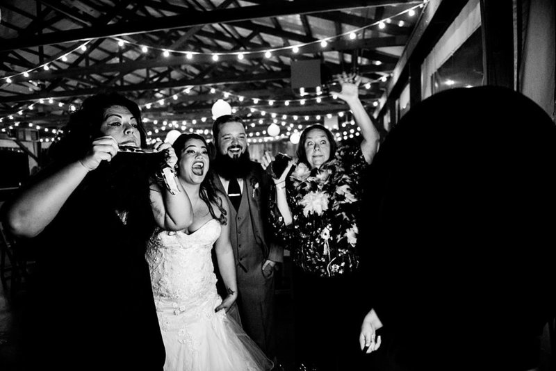 Black and White photo of Bride and groom having fun in photobooth with family members