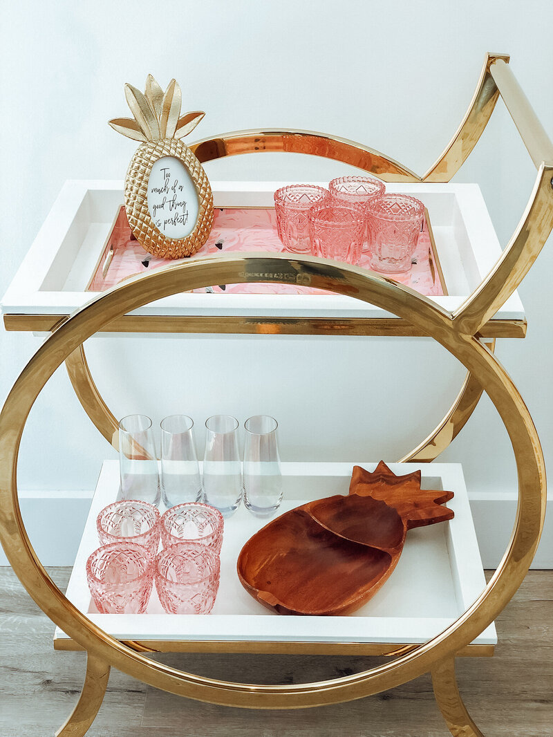Bar cart with pineapple decor and pink glassware in The Surf House vacation rental, Panama City Beach