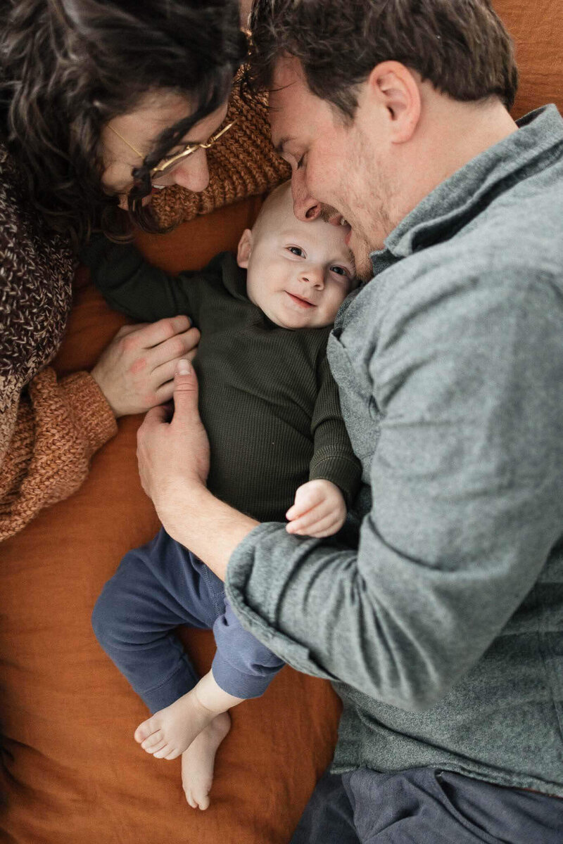 A cozy family moment with parents snuggling their baby during a Cleveland newborn photography session.
