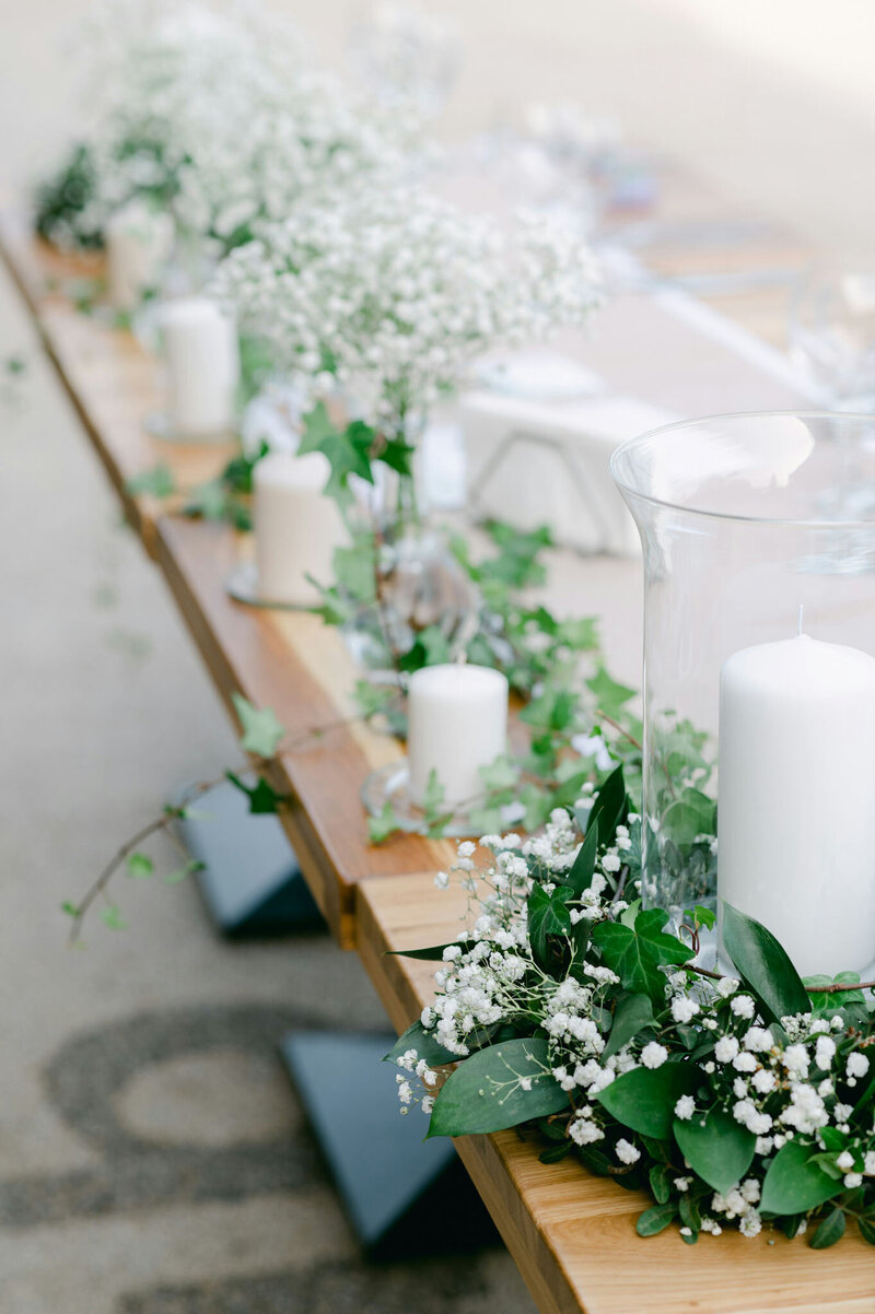 Rustic wedding table decor with greenery, white candles, and baby’s breath