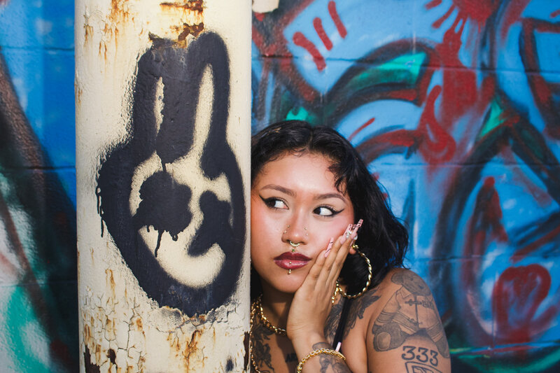 Mahal posing next to a pole with a spraypainted buny and looking at the x's the bunny has for eyes.