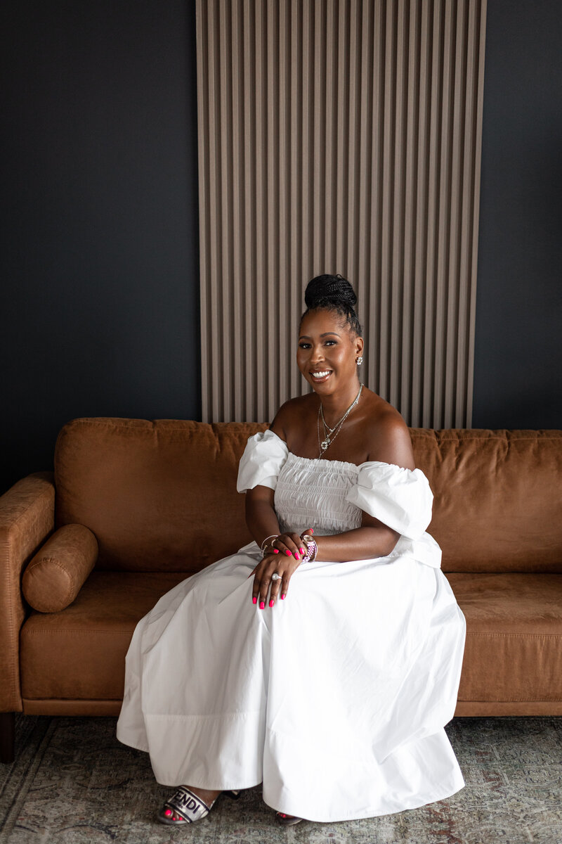 A woman smiling while sitting on a brown sofa