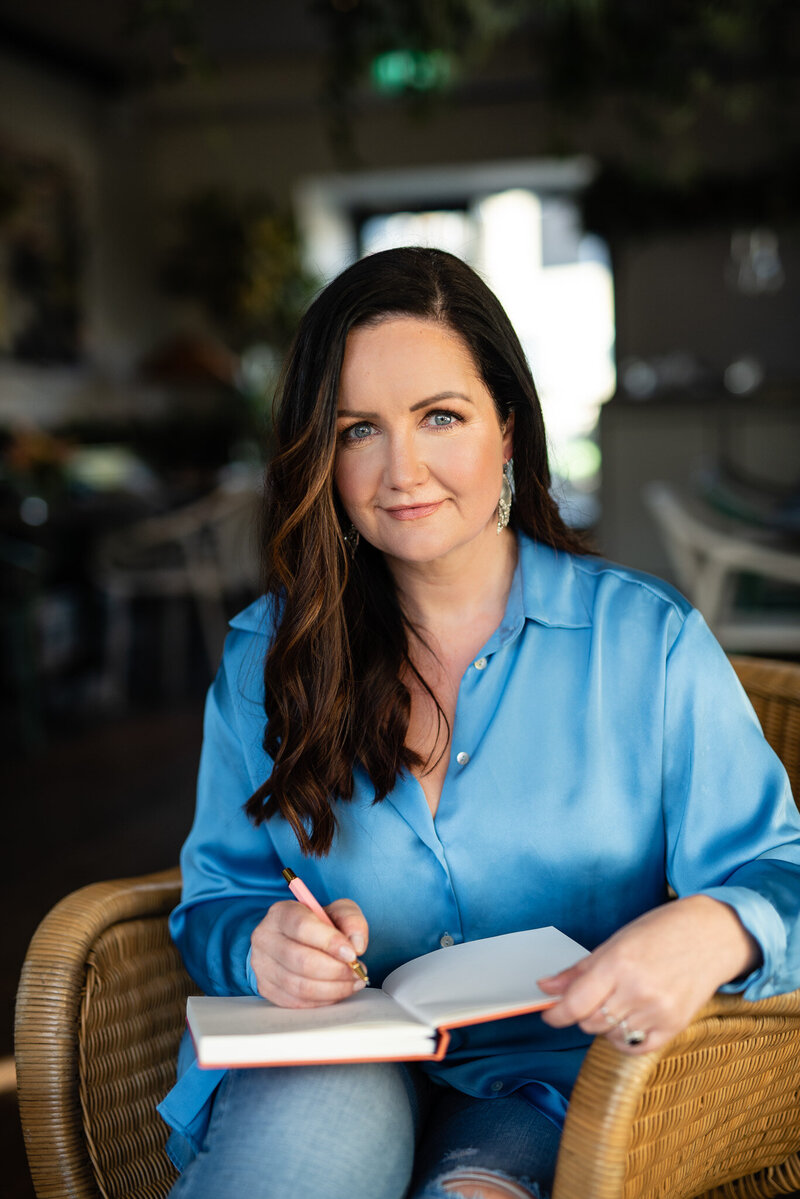 Bryony Williams in blue shirt writing to a notebook