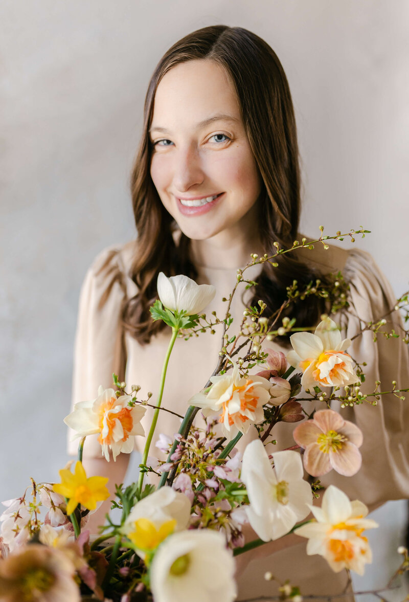 woman putting flowers in overhead installation