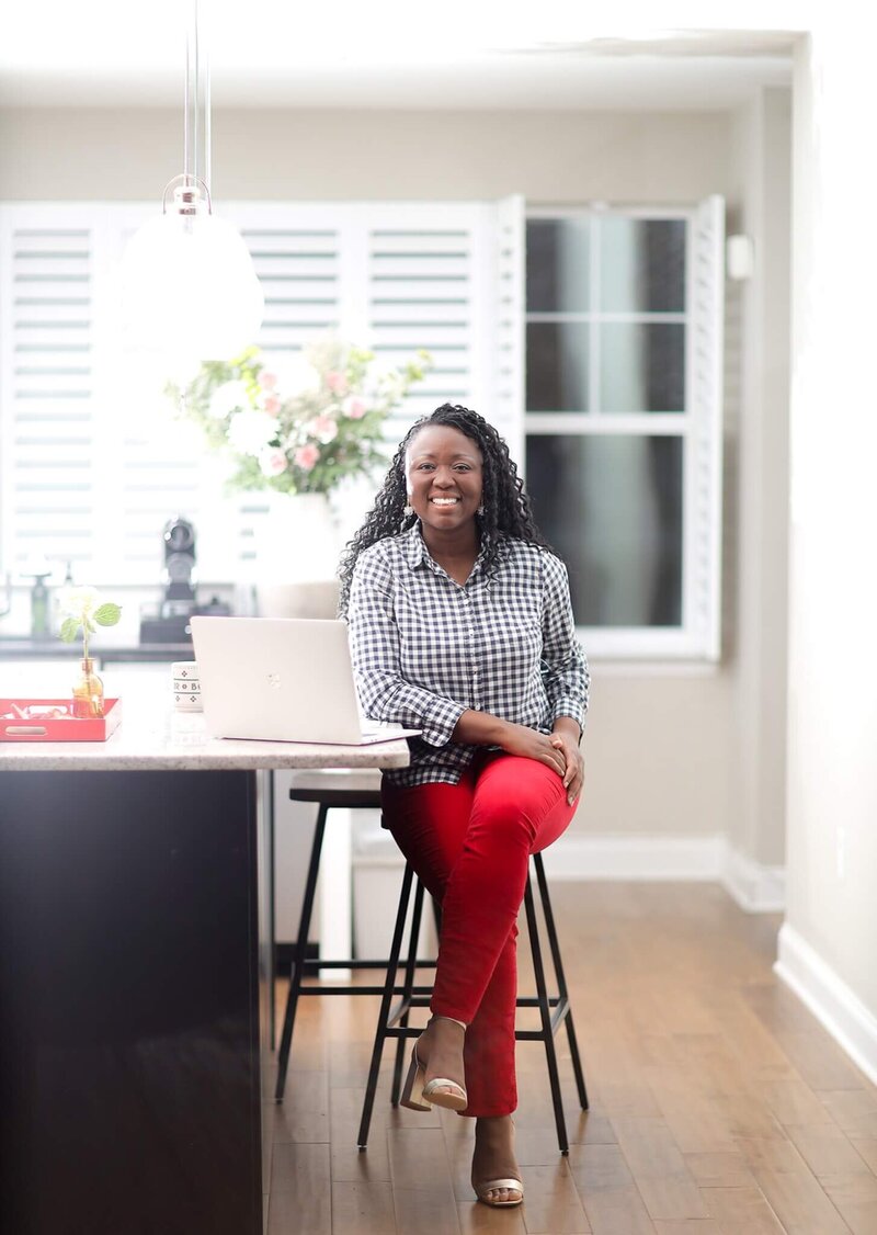 Speaking & Confidence Coach Brenda Chadambura Sitting on a Kitchen Stool With A Laptop - Brenda Chadambura