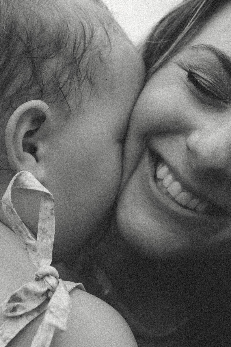 Close-up of little girl squishing her face into moms as she smiles during family session on farm