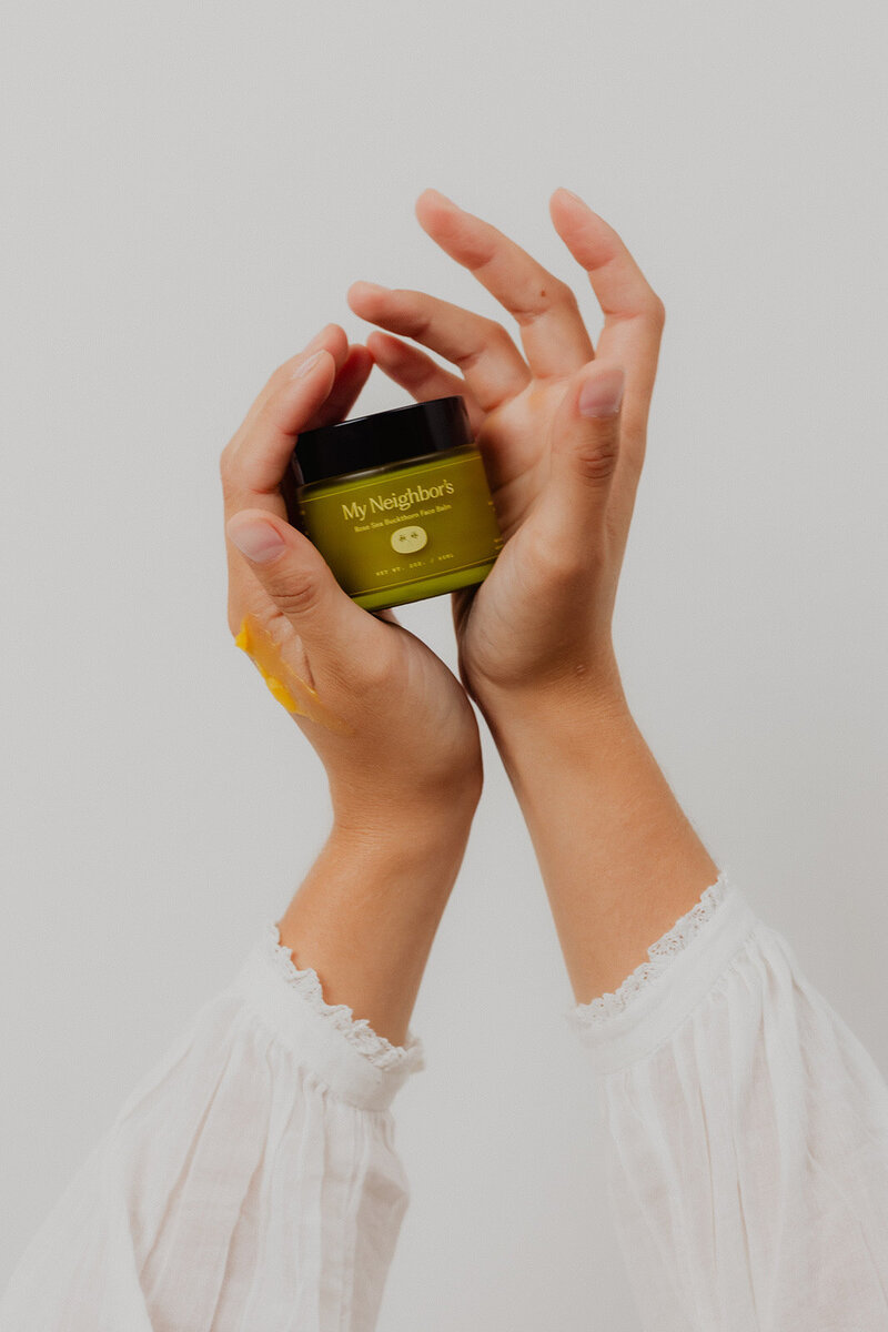 hands holding my neighbor's tallow jar on a white backdrop