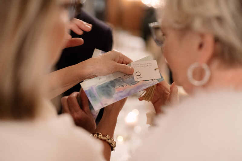 November wedding at Graylyn Estate, designed and planned by Charming Carolina — guests looking at the custom bookmark escort display to find their seat, featuring watercolor art and thank you notes.