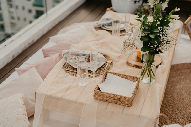 Intimate rooftop picnic table with neutral linens and floral decor