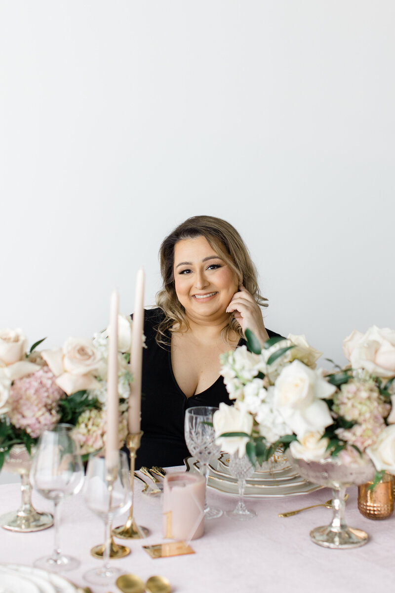 sikh event planner smiling at a dinner table decorated with candles and white roses