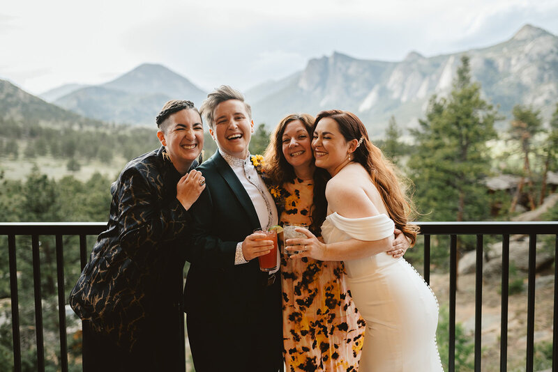4 people standing in front of the mountains, smiling, arms around each other
