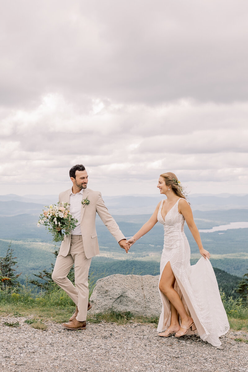 Wedding couple smiling and looking at each other with a view of Lake George behind them during the Fall.