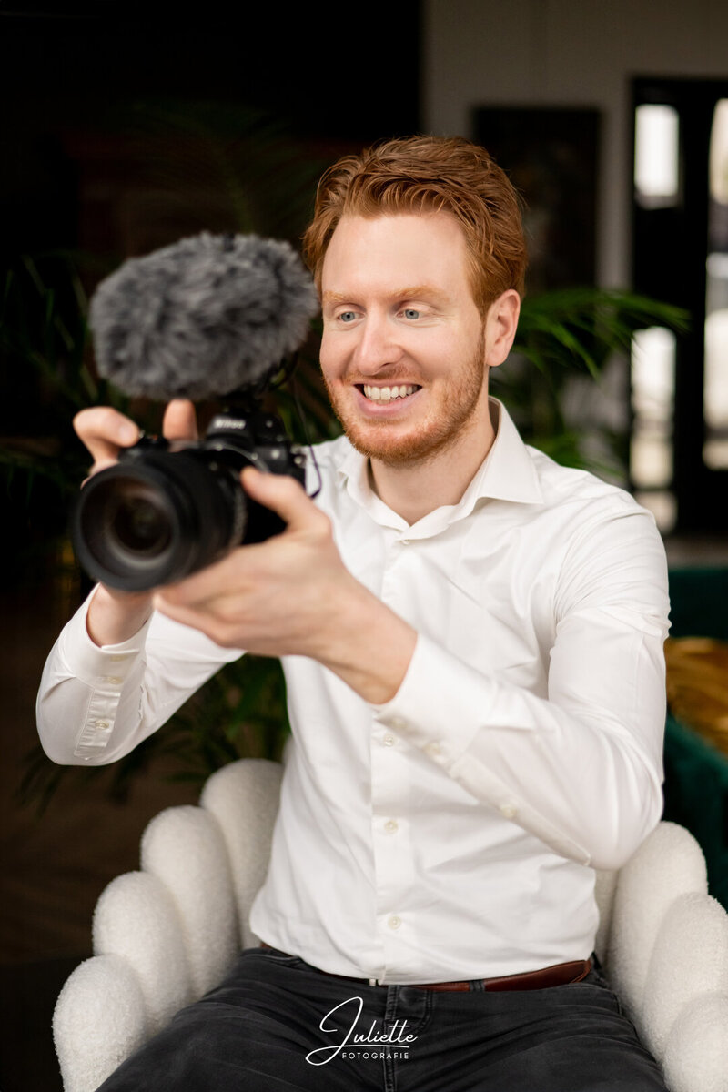 Tibor Laurant met videocamera in de hand met bruine achtergrond