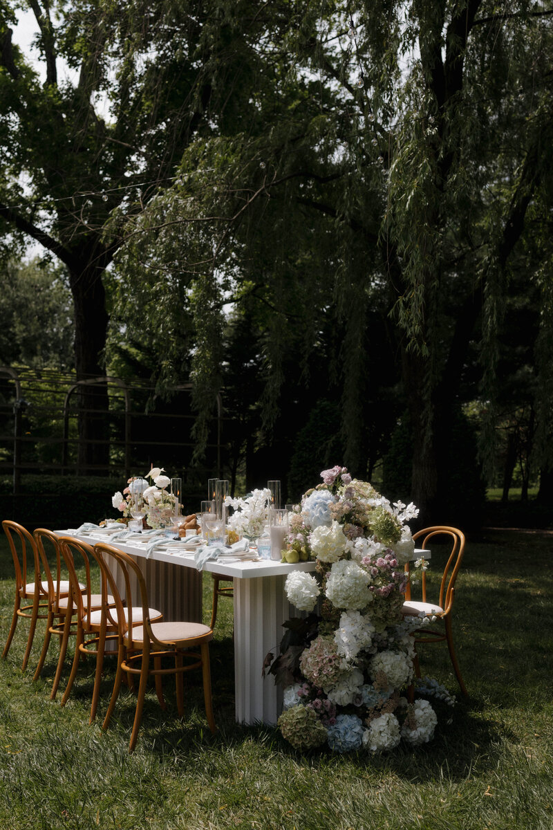 A beautifully decorated wedding reception table adorned with fresh flowers and soft candlelight, set against large windows with scenic views.