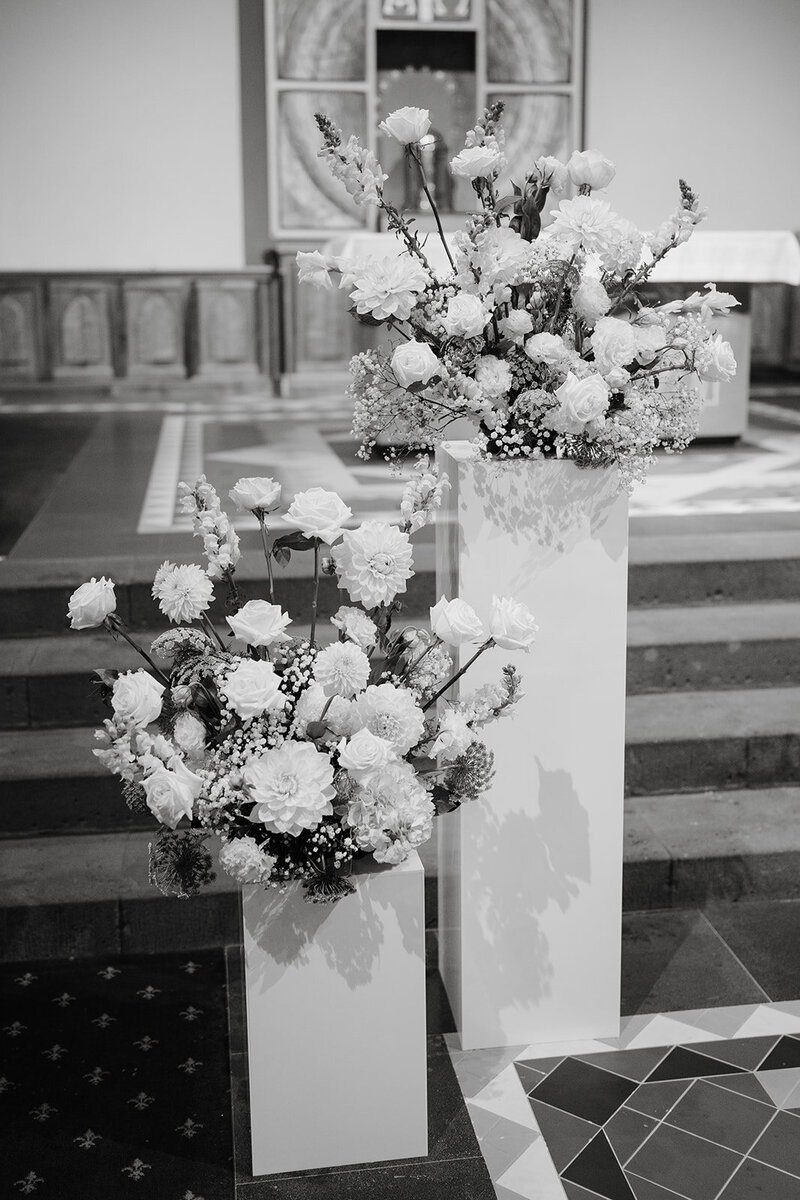 White and green flower arrangements styled on rectangle white plinths
