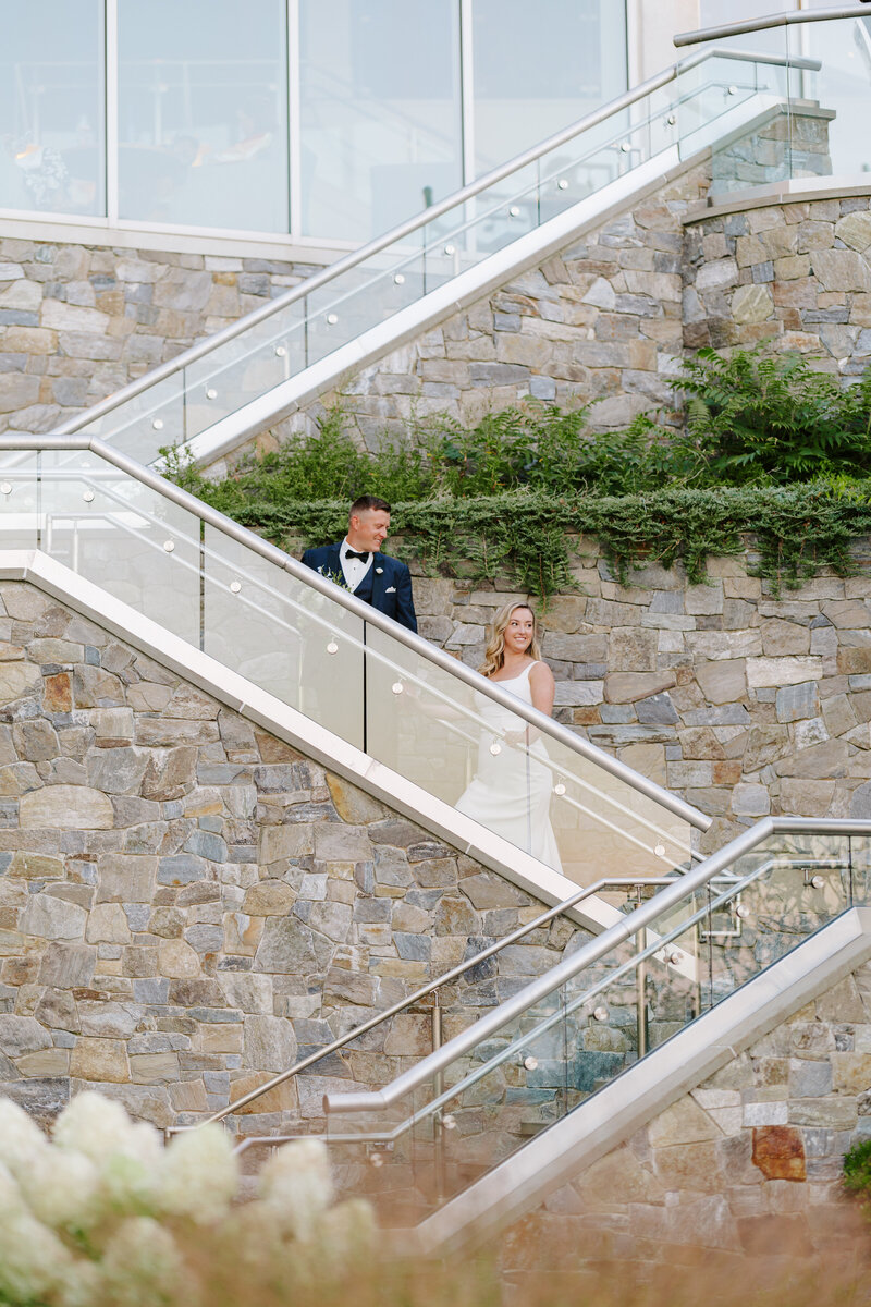 Groom walking with bride up stairs at Cliff House in Maine taken by amazing wedding photographer