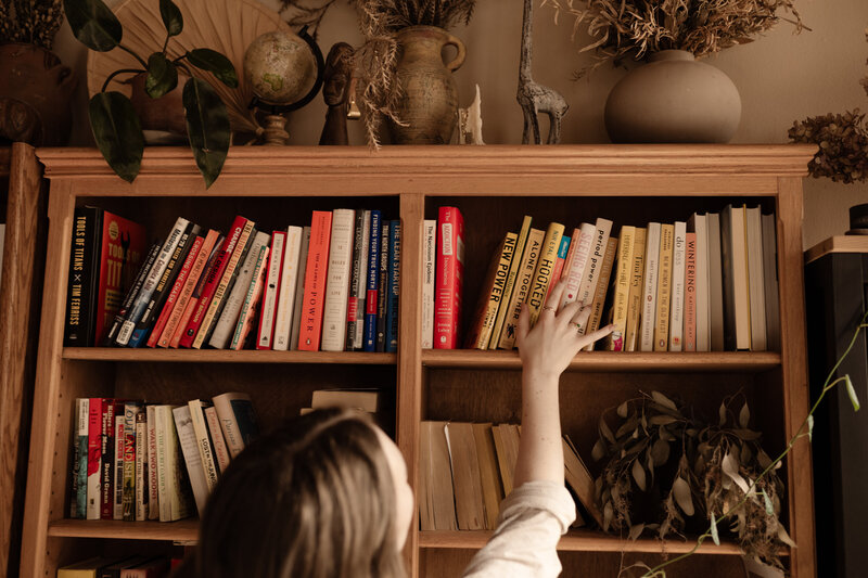 Copywriter reaching for a book on a shelf