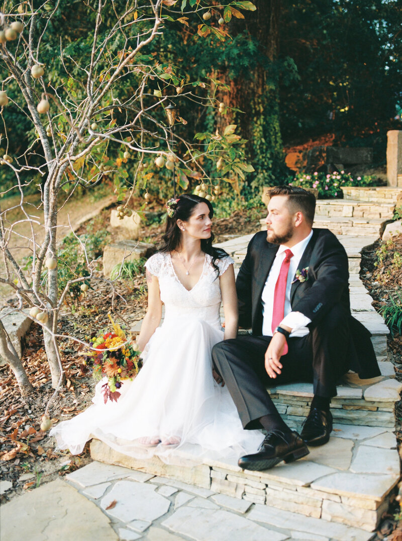 bride and groom sitting on stone stairs looking at each other in kentucky