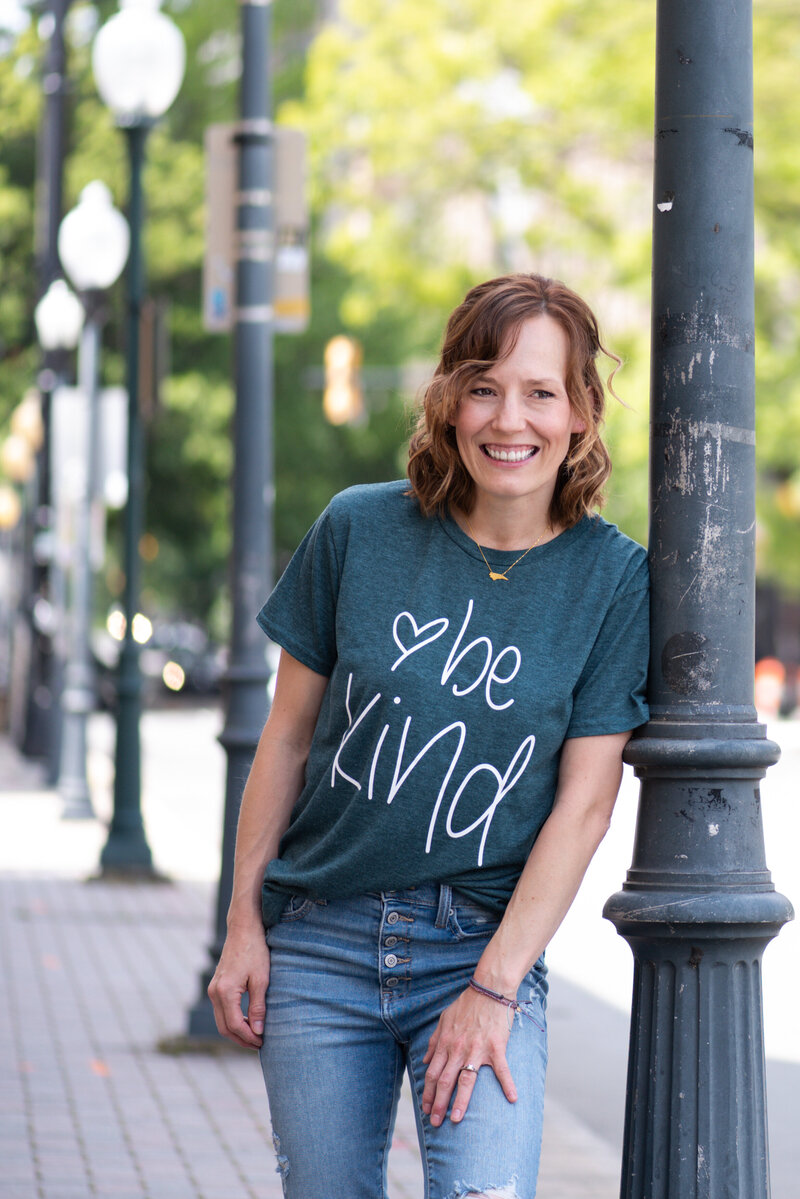 Shannon posing in a be kind shirt in Uptown Charlotte North Carolina during her brand photography session.