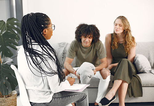 Therapist in session with a couple sitting on a couch.